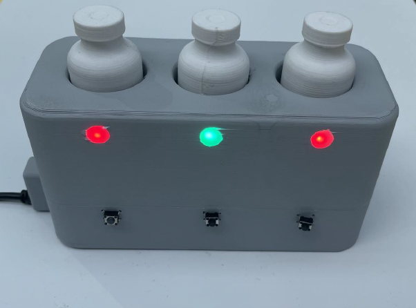 3D-printed opened-vial rack holding three lidocaine vials, with two slots glowing green (still usable) and one glowing red (past three-day shelf-life).